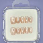 Mabel and Honey’s Pearl set features ten salon-quality press-on nails in glossy nude shades, displayed in two rows inside a clear plastic case with a purple background.