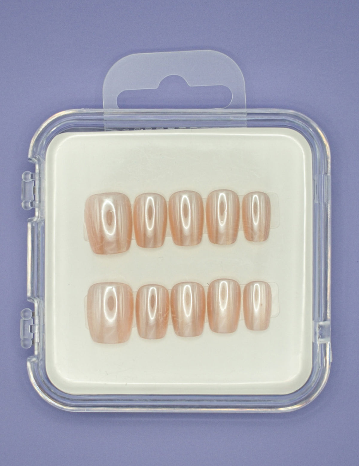 Mabel and Honey’s Pearl set features ten salon-quality press-on nails in glossy nude shades, displayed in two rows inside a clear plastic case with a purple background.