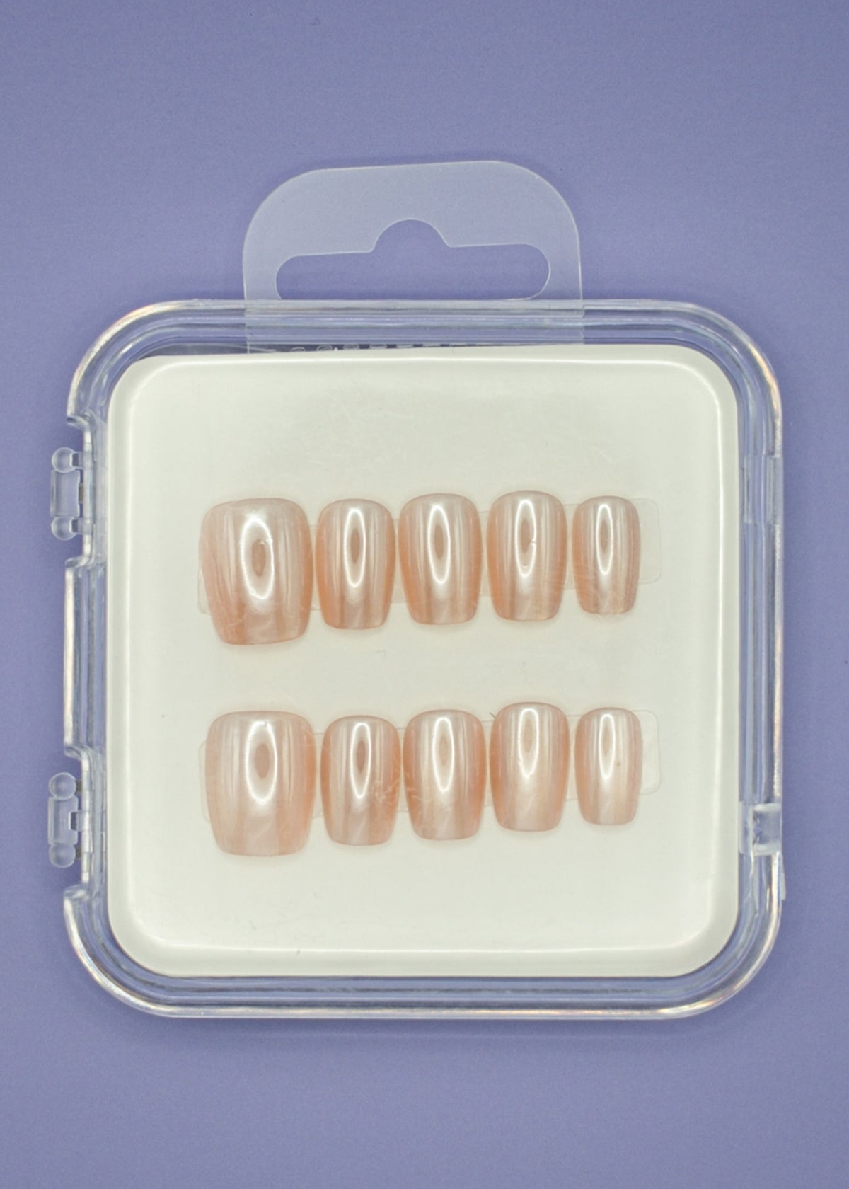 Mabel and Honey’s Pearl set features ten salon-quality press-on nails in glossy nude shades, displayed in two rows inside a clear plastic case with a purple background.
