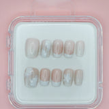 Mabel and Honey's White Floral press-on nails come in a clear case, featuring a pale pink base with white floral details and French tips, displayed on a light pink background.