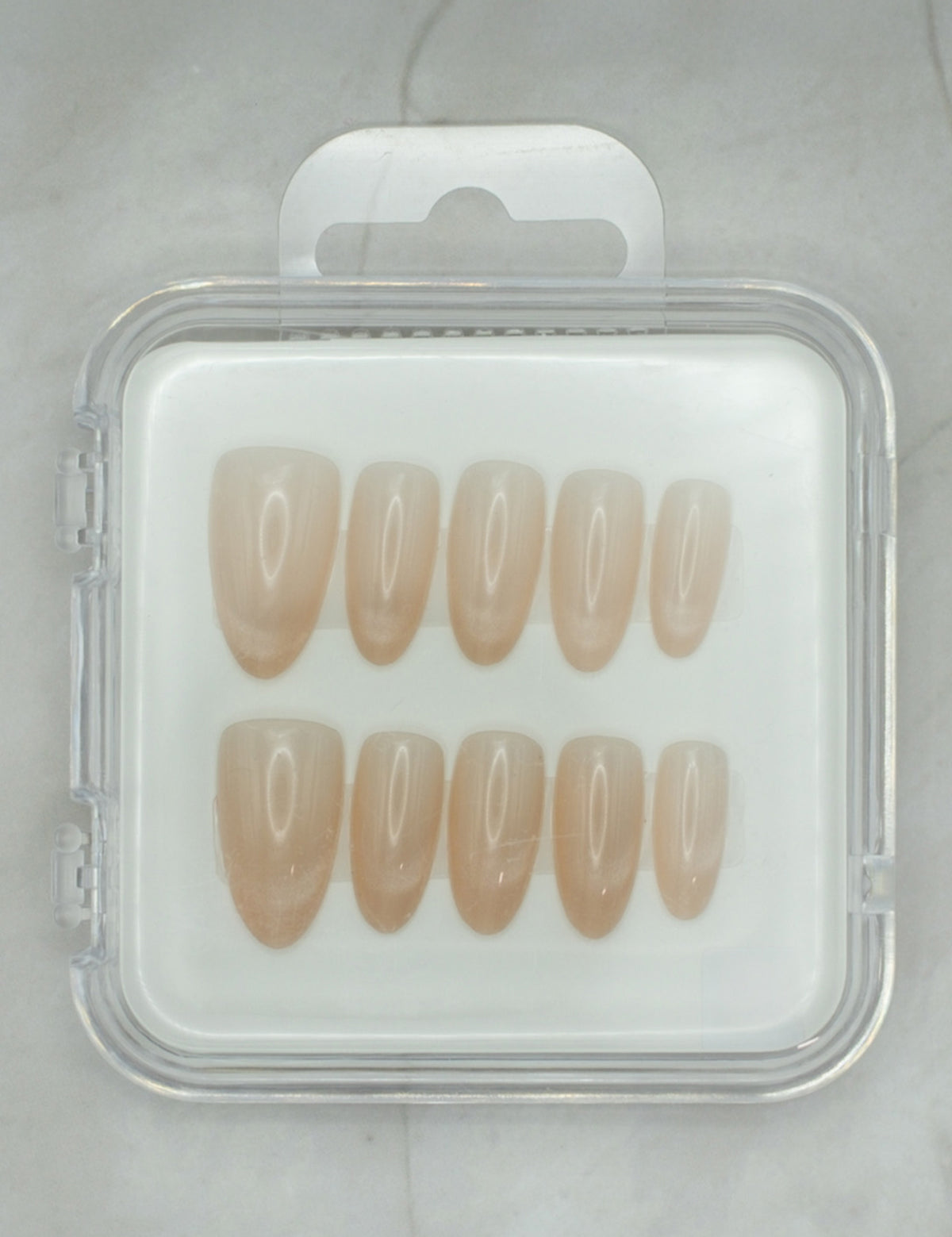 Soft Sand by Mabel and Honey features eight nude press-on nails in a clear case, shown on light gray marble—perfect for salon-quality manicures at home.