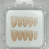 Soft Sand by Mabel and Honey features eight nude press-on nails in a clear case, shown on light gray marble—perfect for salon-quality manicures at home.