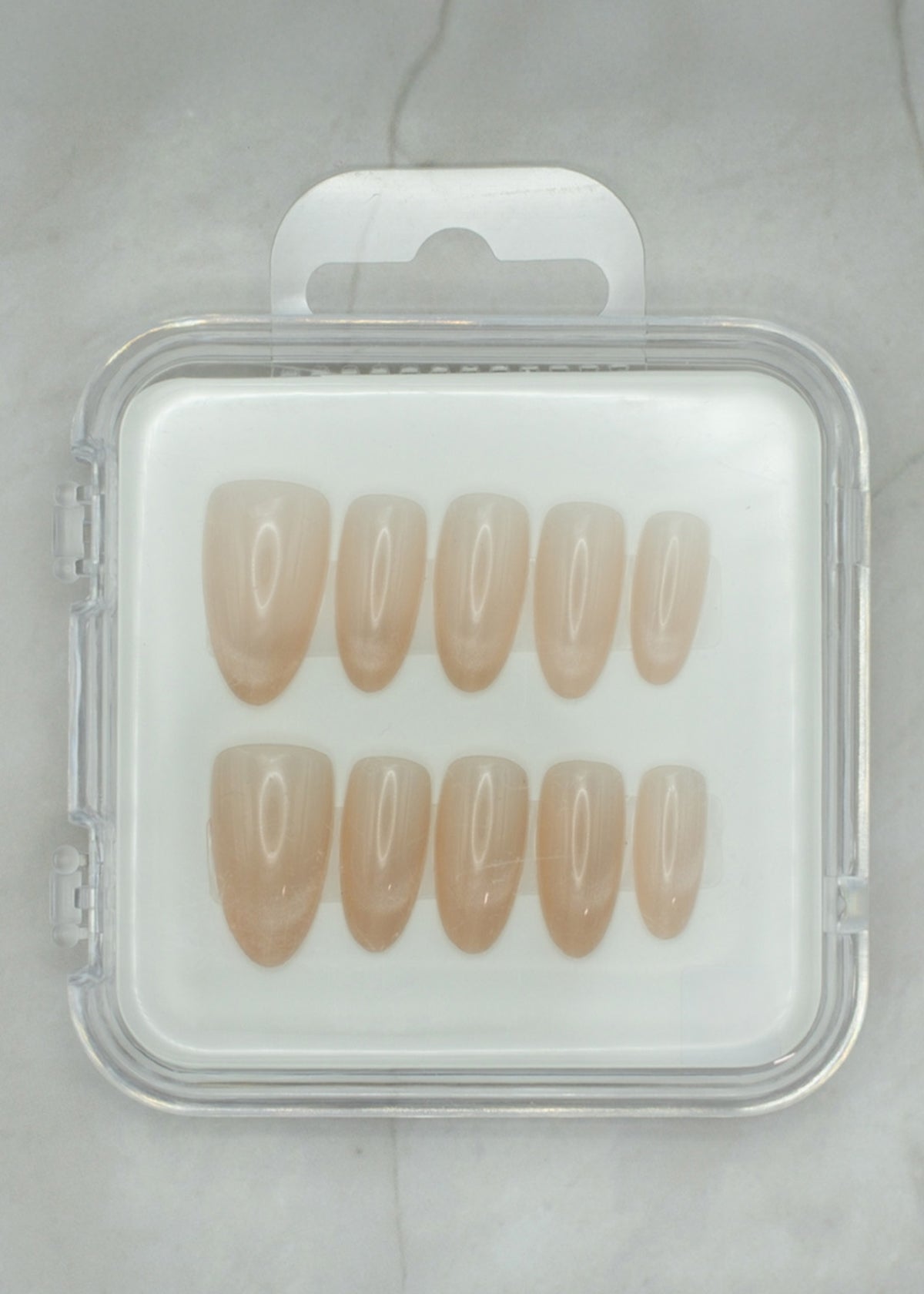 Soft Sand by Mabel and Honey features eight nude press-on nails in a clear case, shown on light gray marble—perfect for salon-quality manicures at home.