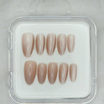 Sheer Delight by Mabel and Honey features ten glossy, almond-shaped nude press-on nails in a clear case, arranged in two rows on a light surface—perfect for achieving a salon-quality manicure at home.