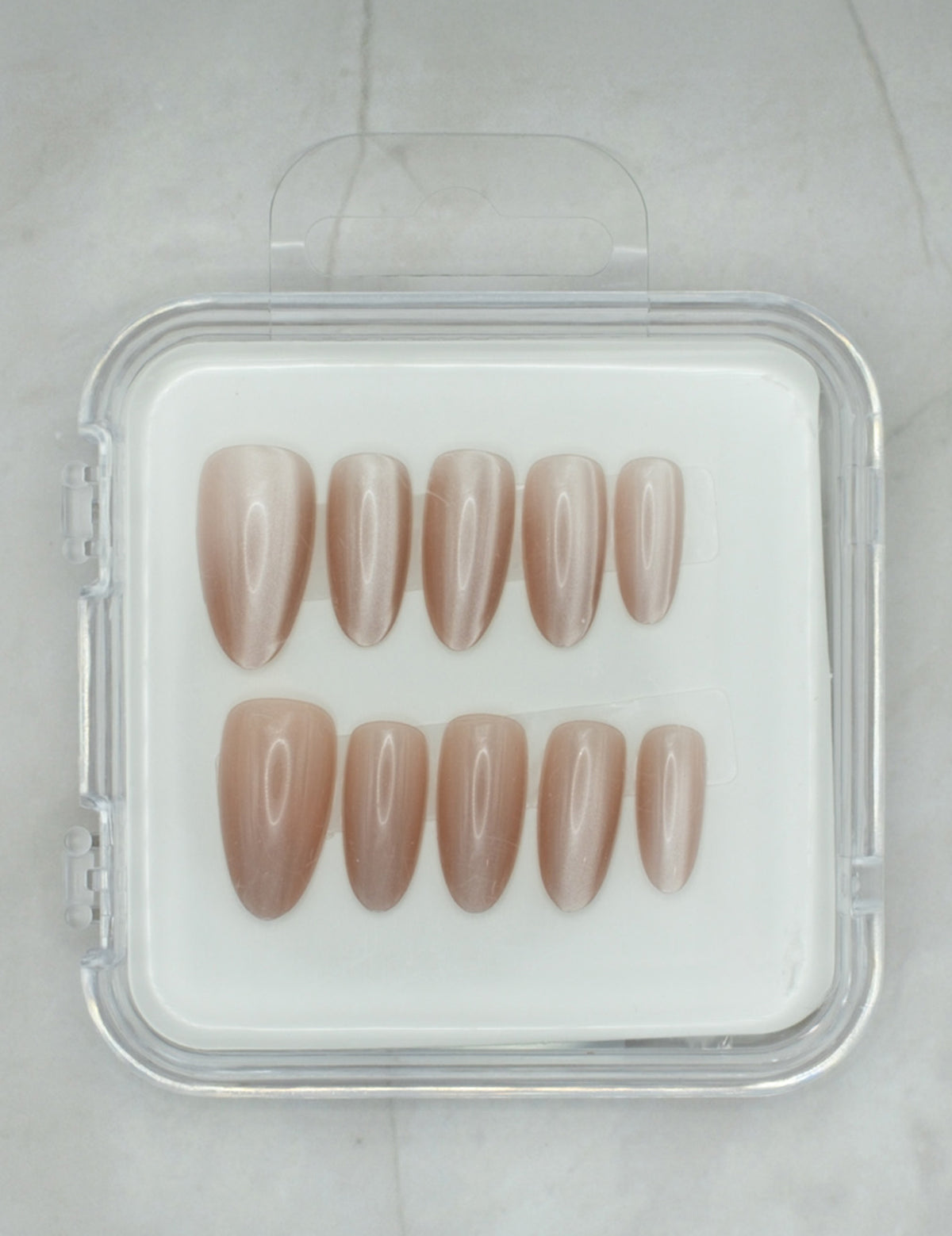 Sheer Delight by Mabel and Honey features ten glossy, almond-shaped nude press-on nails in a clear case, arranged in two rows on a light surface—perfect for achieving a salon-quality manicure at home.