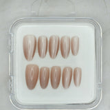 Sheer Delight by Mabel and Honey features ten glossy, almond-shaped nude press-on nails in a clear case, arranged in two rows on a light surface—perfect for achieving a salon-quality manicure at home.