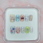Teddy Bear Dreams by Mabel and Honey features ten reusable salon-quality press-on nails in a cute clear case. Each pastel nail has colorful designs—bears, bows, cherries, and flowers—perfect for stylish nails anytime.