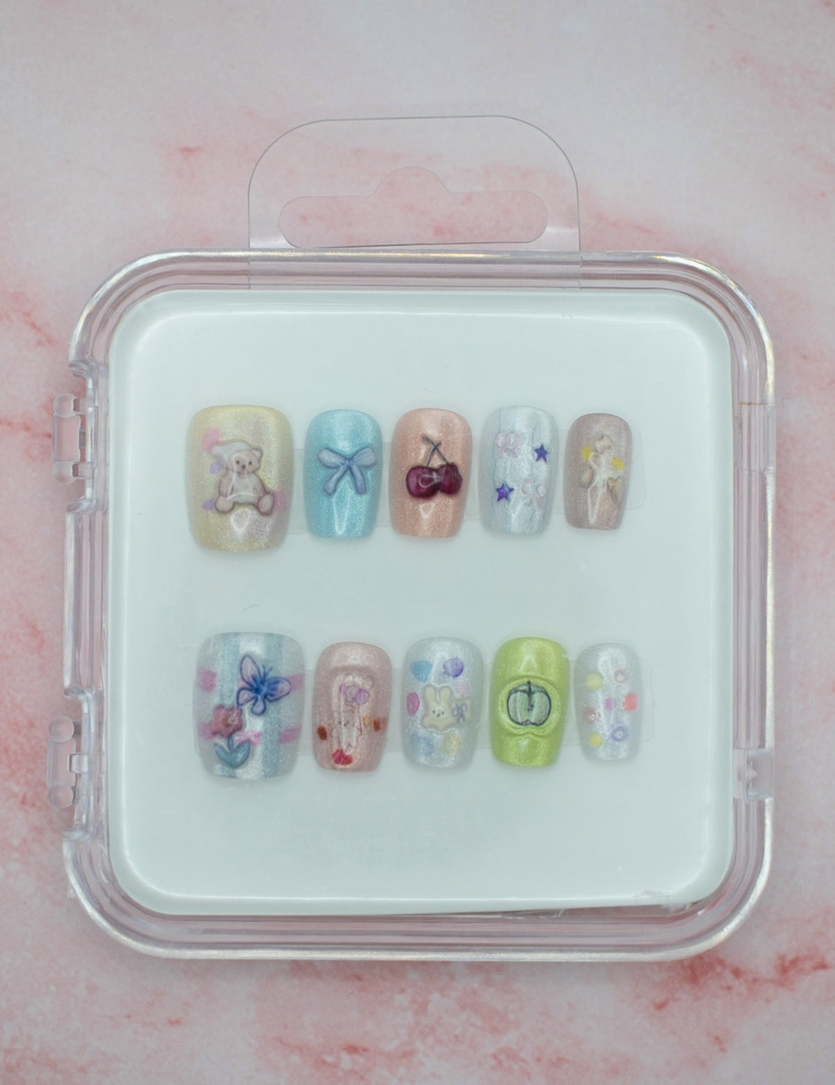Teddy Bear Dreams by Mabel and Honey features ten reusable salon-quality press-on nails in a cute clear case. Each pastel nail has colorful designs—bears, bows, cherries, and flowers—perfect for stylish nails anytime.