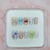 Teddy Bear Dreams by Mabel and Honey features ten reusable salon-quality press-on nails in a cute clear case. Each pastel nail has colorful designs—bears, bows, cherries, and flowers—perfect for stylish nails anytime.