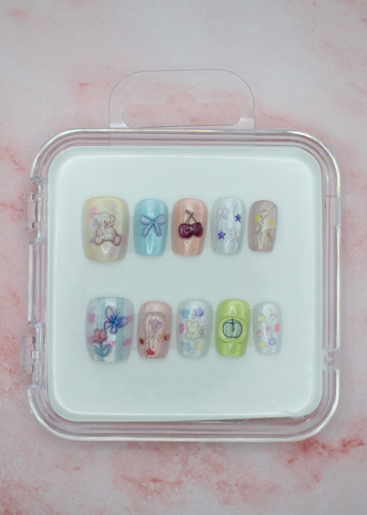 Teddy Bear Dreams by Mabel and Honey features ten reusable salon-quality press-on nails in a cute clear case. Each pastel nail has colorful designs—bears, bows, cherries, and flowers—perfect for stylish nails anytime.