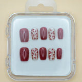 Wild Thing by Mabel and Honey is a set of salon-quality, reusable press-on nails in a plastic case, featuring solid burgundy and beige with burgundy leopard spots, all neatly arranged in two rows.