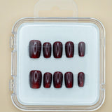 Red Amber by Mabel and Honey features ten dark red, glossy press-on nails arranged in two rows inside a clear case, perfect for achieving a salon-quality manicure at home.