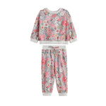The Eliza Two Piece Set by Mabel + Honey features a long-sleeve floral sweatshirt and matching joggers, both adorned with pink, white, and blue flowers and finished with light gray ribbed cuffs and waistband—making this charming set perfect for any occasion.