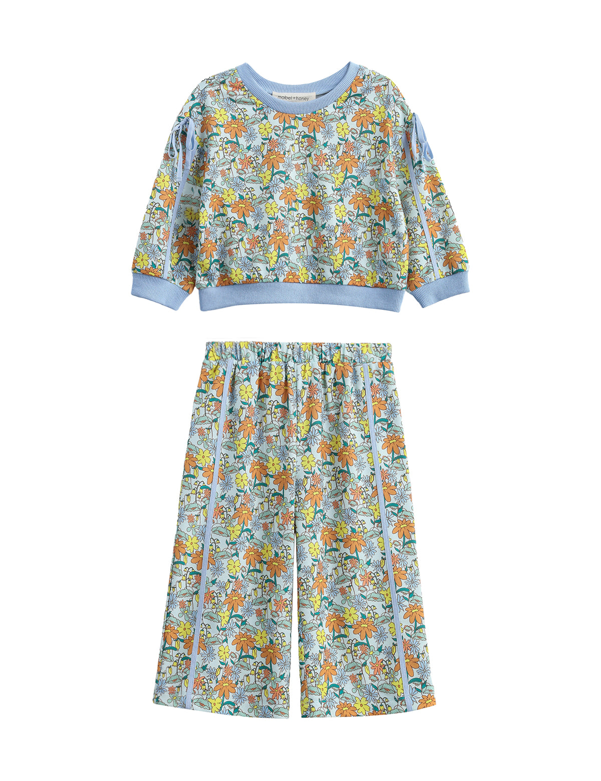 The Ivy Bloom Two Piece Set by Mabel + Honey features a long-sleeve floral sweatshirt paired with coordinating wide-leg pants. Adorned in light blue with a vibrant animal and nature print accented by playful daisies and finished with solid blue trim at the cuffs, neckline, and waistband, this charming set is perfect for cozy nights and sweet dreams.
