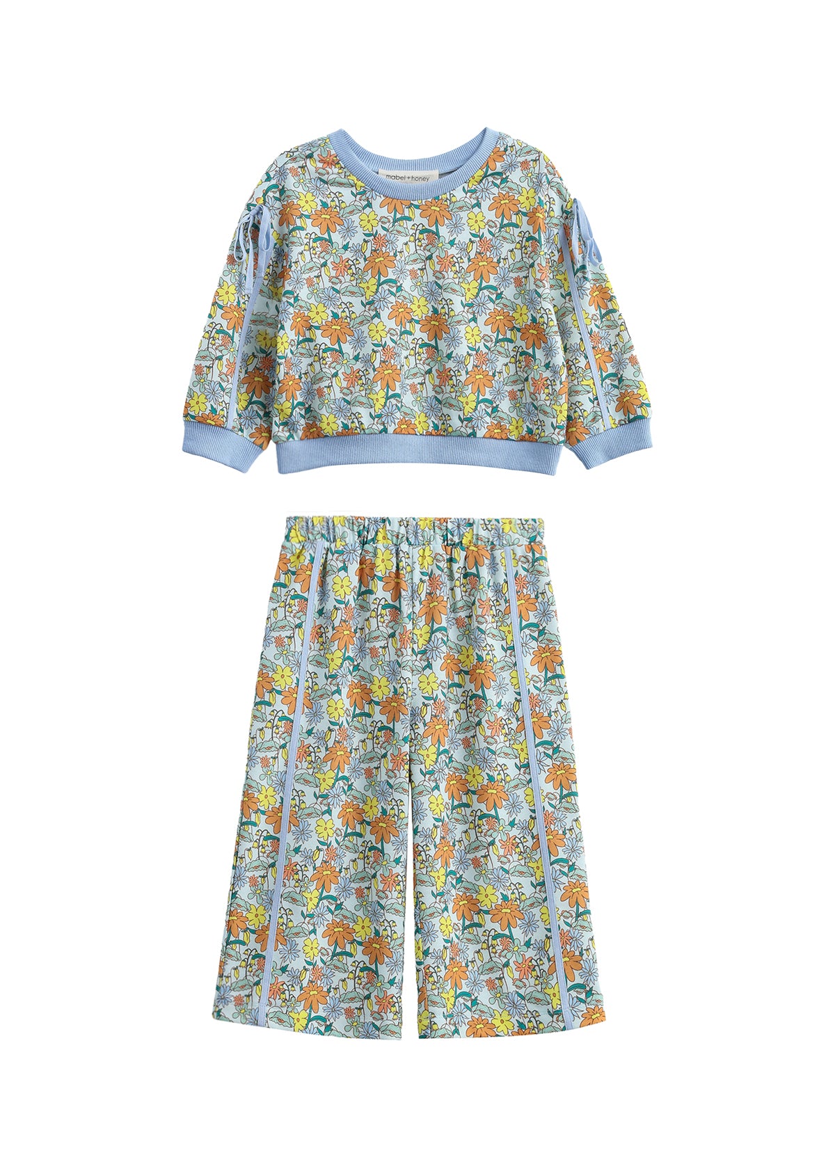 The Ivy Bloom Two Piece Set by Mabel + Honey features a long-sleeve floral sweatshirt paired with coordinating wide-leg pants. Adorned in light blue with a vibrant animal and nature print accented by playful daisies and finished with solid blue trim at the cuffs, neckline, and waistband, this charming set is perfect for cozy nights and sweet dreams.