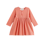 The Persimmon Long Sleeve Waffle Knit Button Placket A Line Dress by Mabel and Honey is a children’s dress in coral pink and white gingham, featuring long sleeves, a round neckline, two buttons on the chest, and a gathered empire waist skirt. The dress is displayed on a white background.