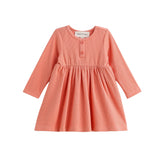 The Persimmon Long Sleeve Waffle Knit Button Placket A Line Dress by Mabel and Honey is a children’s dress in coral pink and white gingham, featuring long sleeves, a round neckline, two buttons on the chest, and a gathered empire waist skirt. The dress is displayed on a white background.