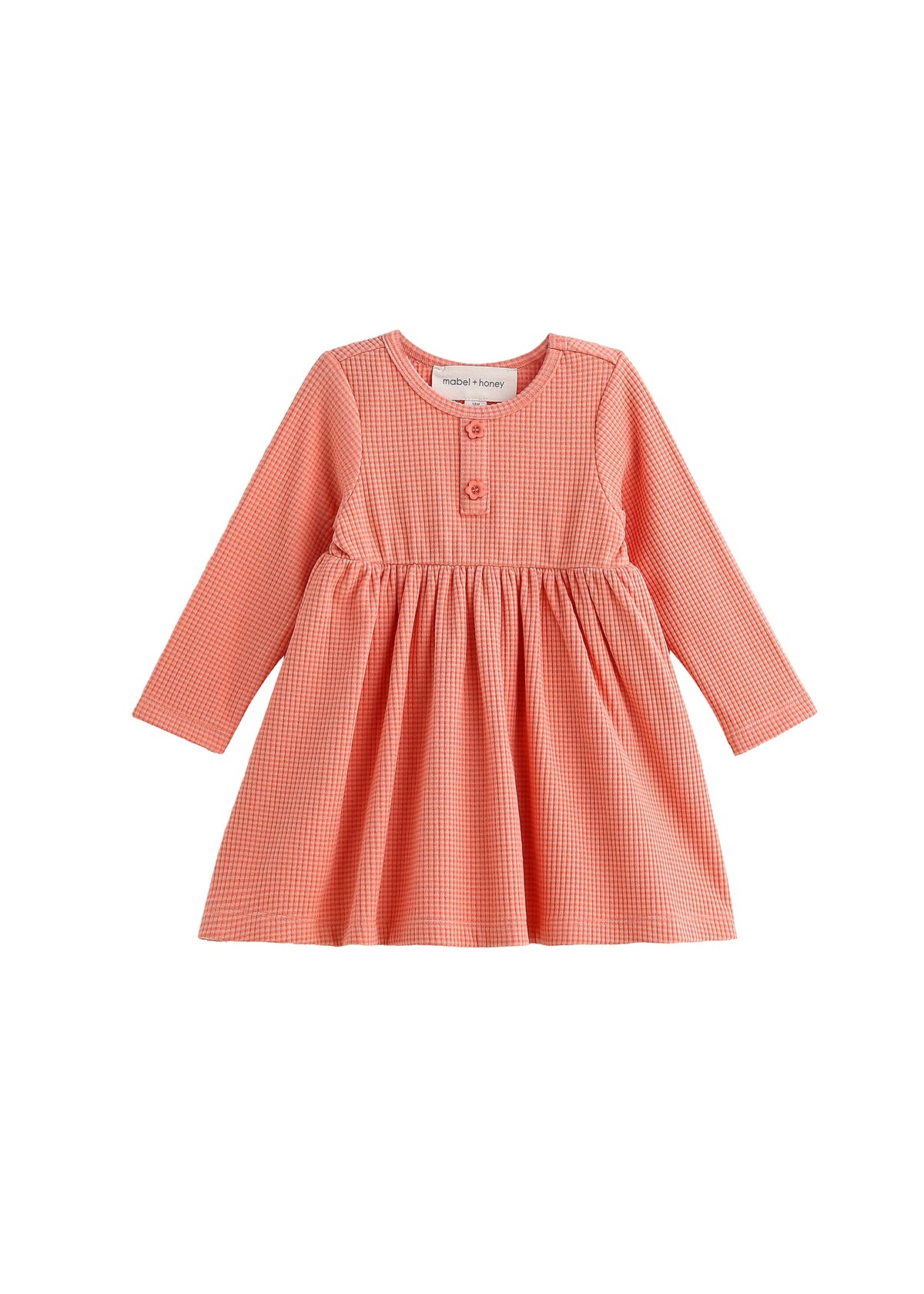 The Persimmon Long Sleeve Waffle Knit Button Placket A Line Dress by Mabel and Honey is a children’s dress in coral pink and white gingham, featuring long sleeves, a round neckline, two buttons on the chest, and a gathered empire waist skirt. The dress is displayed on a white background.