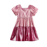The Mabel + Honey Berry Blush Dress is a shiny metallic pink short-sleeve girls’ party dress featuring puffed sleeves, a square neckline, and a color-blocked tiered skirt, displayed on a white background.
