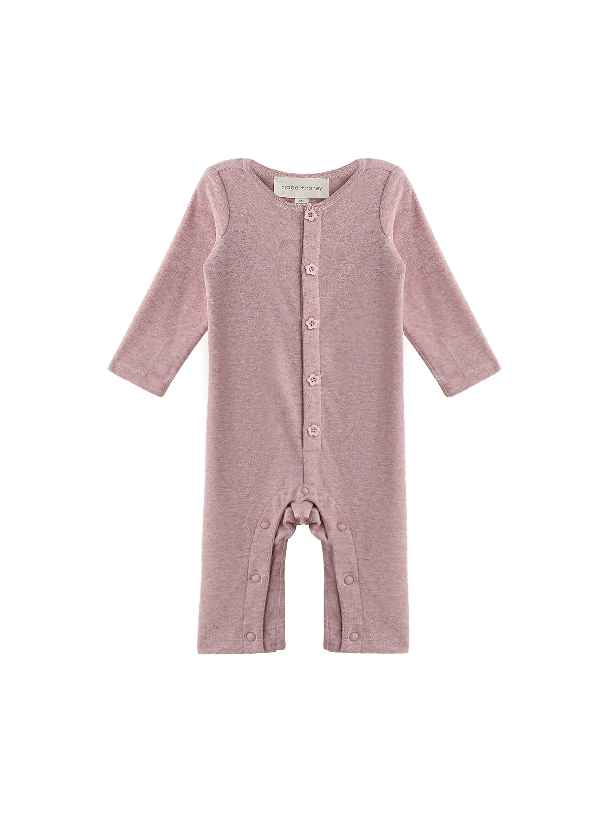 The Mabel + Honey Margret Romper is a long-sleeve, solid heathered pink baby girl romper featuring flower-shaped buttons down the front and along the straight legs, displayed on a white background.