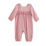 The Rosie Posie Long Sleeve Gingham Ruffle Waist Bubble Romper by Mabel and Honey features a charming red and white coral gingham pattern, ruffle detailing across the chest, and convenient snap buttons along the legs. Crafted from lightweight cotton with a gentle bubble silhouette, this romper is as comfortable as it is adorable.