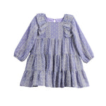 The Mabel + Honey Lavender Lane Dress is a long sleeve dress for young girls, featuring a tiered skirt, ruffle trim on the shoulders, and delicate white embroidery throughout.