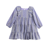The Mabel + Honey Lavender Lane Dress is a long sleeve dress for young girls, featuring a tiered skirt, ruffle trim on the shoulders, and delicate white embroidery throughout.