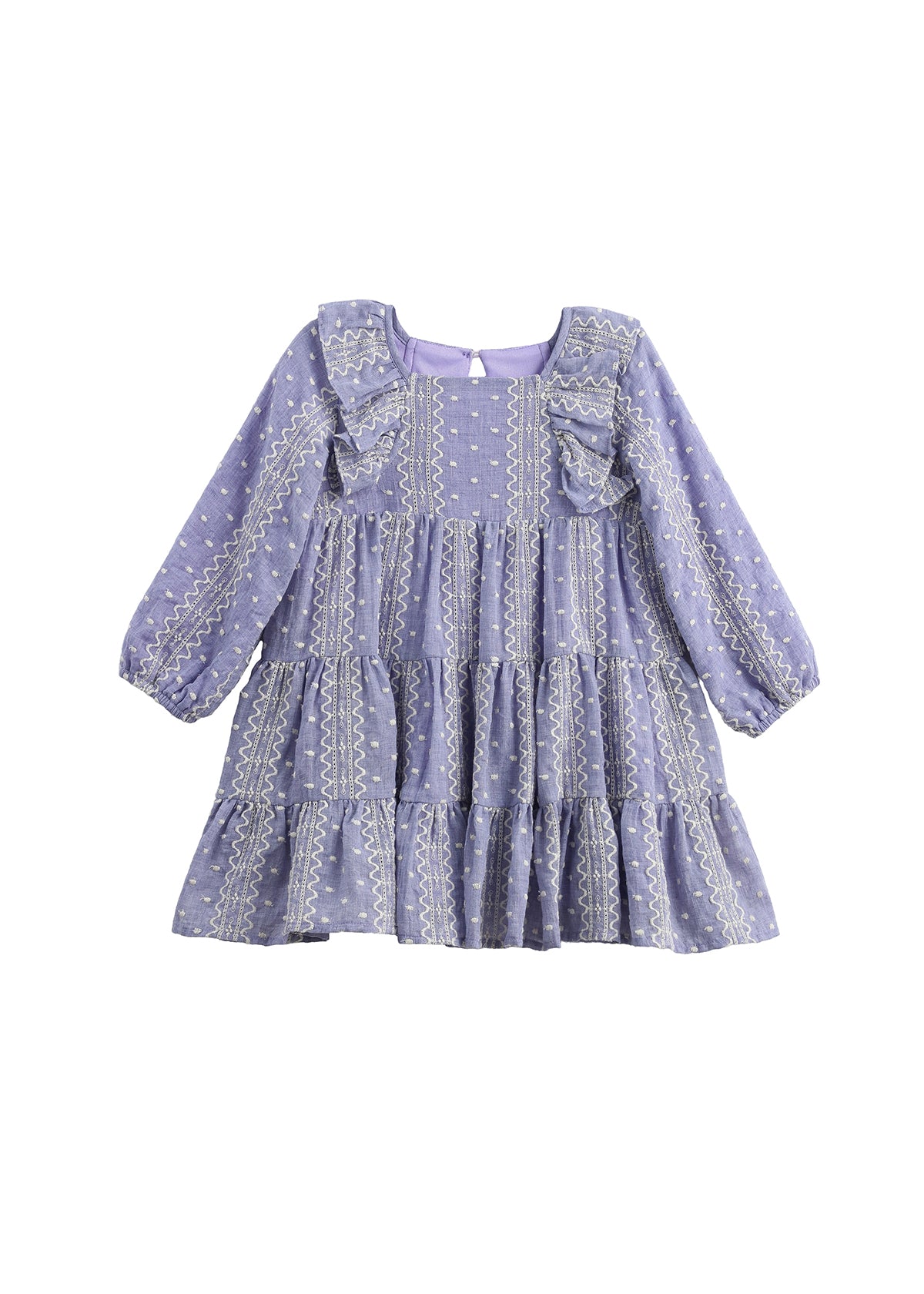 The Mabel + Honey Lavender Lane Dress is a long sleeve dress for young girls, featuring a tiered skirt, ruffle trim on the shoulders, and delicate white embroidery throughout.