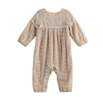 The Patricia Long Sleeve Floral Embroidered Empire Waist Bubble Romper by Mabel and Honey is a light brown baby romper made from a lightweight cotton blend, adorned with delicate white floral embroidery and finished with button closures at the back, shown against a white background.