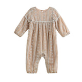 The Patricia Long Sleeve Floral Embroidered Empire Waist Bubble Romper by Mabel and Honey is a light brown baby romper made from a lightweight cotton blend, adorned with delicate white floral embroidery and finished with button closures at the back, shown against a white background.