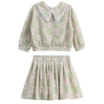 Introducing the Olive Two Piece Set by Mabel + Honey—a charming children’s outfit featuring a long-sleeve top with an elegant floral lace collar and a coordinating skirt. Both pieces showcase a stylish sage green hue adorned with delicate floral patterns, offering an adorable and refined option for everyday wear that stands out from typical checkered or novelty-print sets.