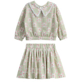 Introducing the Olive Two Piece Set by Mabel + Honey—a charming children’s outfit featuring a long-sleeve top with an elegant floral lace collar and a coordinating skirt. Both pieces showcase a stylish sage green hue adorned with delicate floral patterns, offering an adorable and refined option for everyday wear that stands out from typical checkered or novelty-print sets.