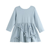 The Eva Dress Long Sleeve Textured A Line Bow Trim Dress by Mabel + Honey is a dusty blue cotton-blend girls’ dress featuring a textured knit pattern, long sleeves, a round neckline, and a flared skirt accented with three decorative bows on the front.