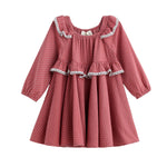 A long-sleeved, knee-length Maribelle Dress Long Sleeve Polka Dot A Line Dress by Mabel + Honey, featuring a dusty rosewood color with white polka dots, ruffled detailing, lace trim, and gathered elastic cuffs, designed for a young child.
