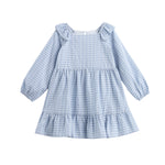 The Ella Rae Dress by Mabel + Honey is a long-sleeve girls’ cotton dress featuring light blue plaid, ruffled shoulders, a charming heart accent, and a tiered, gathered skirt.