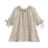 The Mabel and Honey Autumn Breeze Three Quarter Sleeve Floral Ruffle Neck Tie Cuff A Line Dress features a cream-colored floral print, ruffled neckline, gathered collar, and charming bow ties at the cuffs. Designed with a loose, flared silhouette from soft cotton gauze for comfortable wear.