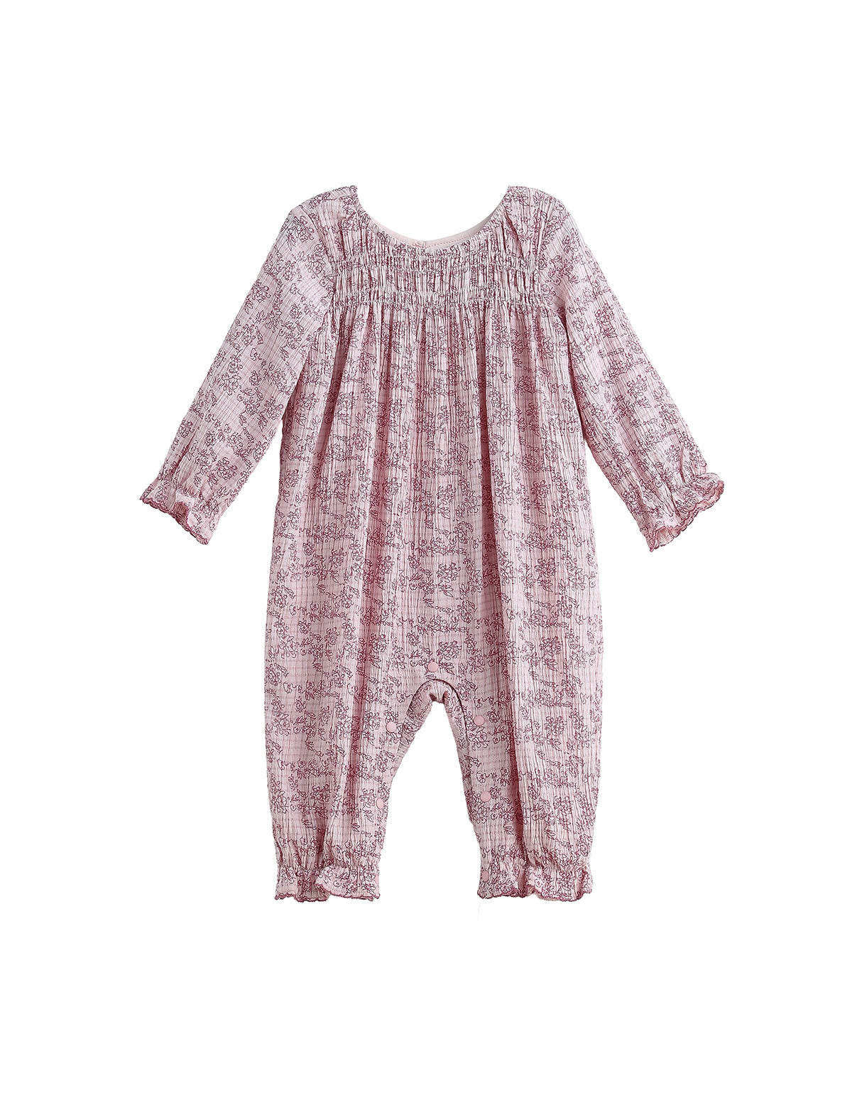 The Loretta Romper Long Sleeve Floral Smocked Straight Leg Romper by Mabel + Honey is shown on a white background, featuring a light pink fabric with a subtle floral print, smocked yoke, gathered neckline, and ruffled cuffs at the sleeves and ankles.