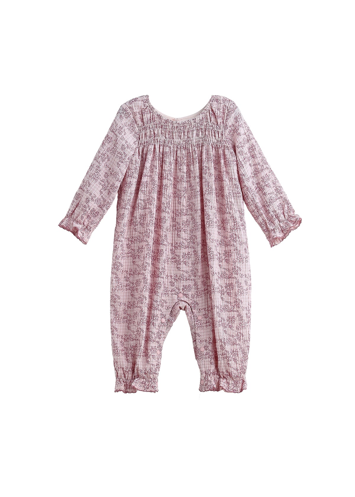 The Loretta Romper Long Sleeve Floral Smocked Straight Leg Romper by Mabel + Honey is shown on a white background, featuring a light pink fabric with a subtle floral print, smocked yoke, gathered neckline, and ruffled cuffs at the sleeves and ankles.