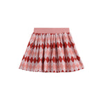 The Jessica Argyle Print Ribbed Waistband Gathered Skirt by Mabel and Honey features a pink pleated design with red and light pink argyle diamond patterns. The skirt has a comfortable ribbed elastic waistband and is shown against a white background.