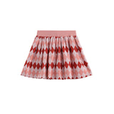 The Jessica Argyle Print Ribbed Waistband Gathered Skirt by Mabel and Honey features a pink pleated design with red and light pink argyle diamond patterns. The skirt has a comfortable ribbed elastic waistband and is shown against a white background.
