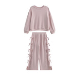 The Emma Two Piece Set Long Sleeve Textured Top And Wide Leg Pant Two Piece Set by Mabel + Honey showcases a light pink, textured knit ensemble with a long-sleeve top and matching wide-leg pants featuring bow-tied details and an elastic waistband, all presented against a white background.