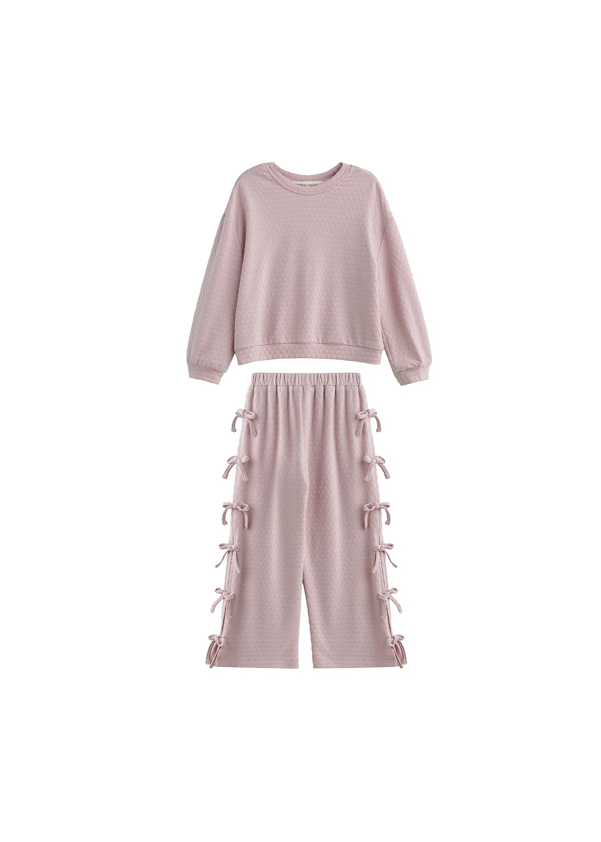 The Emma Two Piece Set Long Sleeve Textured Top And Wide Leg Pant Two Piece Set by Mabel + Honey showcases a light pink, textured knit ensemble with a long-sleeve top and matching wide-leg pants featuring bow-tied details and an elastic waistband, all presented against a white background.