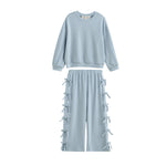 The Eva Two Piece Set Long Sleeve Bow Tie Detail Two Piece Set from Mabel + Honey features a powder blue textured design for children, including a long-sleeve top and wide-leg pants adorned with decorative bows along the sides. This two-piece set offers a relaxed, comfortable fit—perfect for all-day wear.