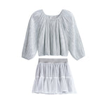 The Shimmer Shine Two Piece Set from Mabel + Honey features a light gray, metallic long sleeve solid top with elegant pleats and a gathered neckline, paired with a white sparkle dot tulle skirt detailed with subtle dots, tiered layers, and a wide waistband—an effortlessly chic ensemble perfect for any occasion.