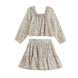 The Autumn Breeze Two Piece Set Long Sleeve Floral Top And Skirt from Mabel + Honey features a delicate, light floral print. The set includes a long-sleeve, ruffled crop top with a square neckline, perfectly matched with a high-waisted, tiered skirt. Both pieces are crafted from lightweight fabric for effortless elegance.