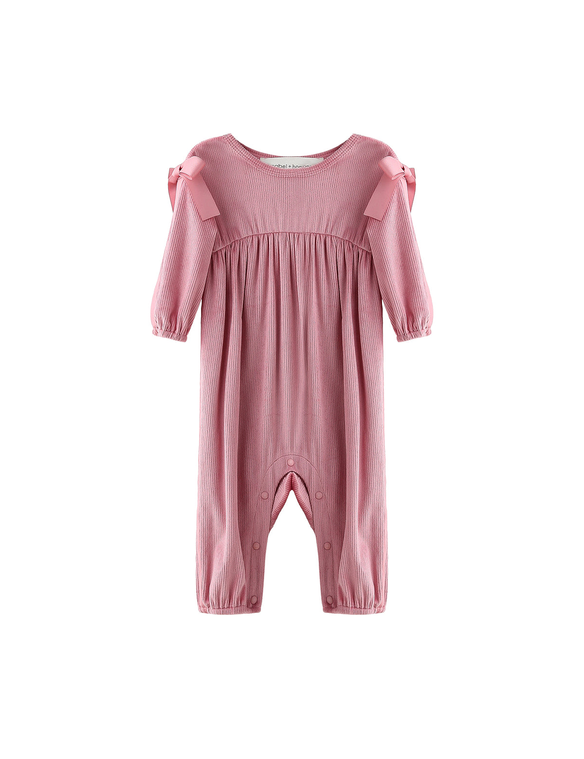 The Mabel + Honey Bowtiful Blush Romper Long Sleeve Solid Ribbed Bubble Leg Shoulder Tie Romper features a dusty rose hue with ribbed fabric, ruffled bubble legs, and charming shoulder ties. Snap buttons along the inseam provide easy dressing, while the romper is displayed on a white background.