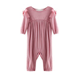 The Mabel + Honey Bowtiful Blush Romper Long Sleeve Solid Ribbed Bubble Leg Shoulder Tie Romper features a dusty rose hue with ribbed fabric, ruffled bubble legs, and charming shoulder ties. Snap buttons along the inseam provide easy dressing, while the romper is displayed on a white background.