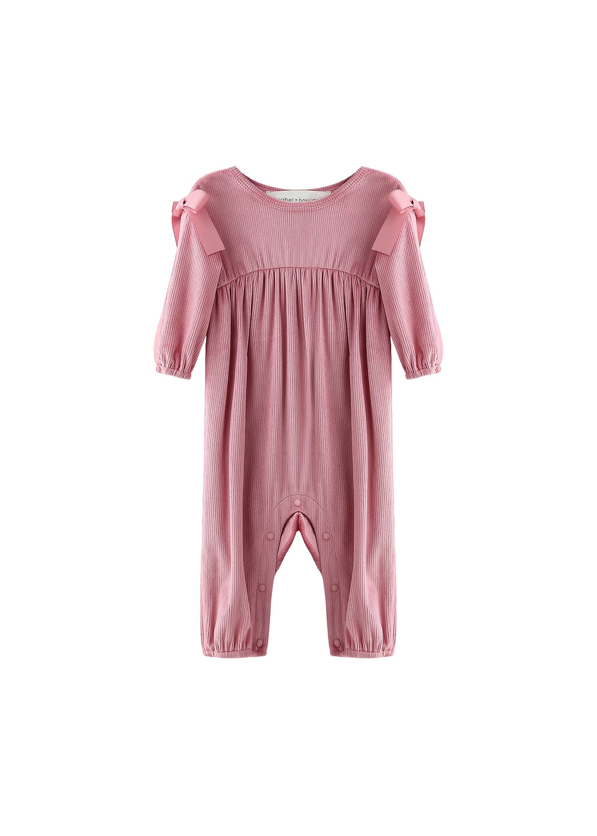 The Mabel + Honey Bowtiful Blush Romper Long Sleeve Solid Ribbed Bubble Leg Shoulder Tie Romper features a dusty rose hue with ribbed fabric, ruffled bubble legs, and charming shoulder ties. Snap buttons along the inseam provide easy dressing, while the romper is displayed on a white background.