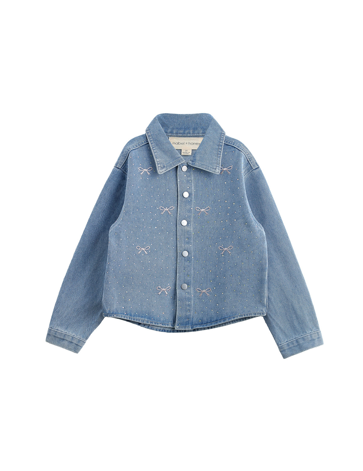 The Mabel + Honey Jacket Long Sleeve Print Rhinestone Bow Detail Cropped Denim Jacket features a light blue wash, classic collar, long sleeves, silver snap buttons, and sparkling rhinestone pink bows and dots embroidered on the front. The jacket is displayed laid flat on a white background.