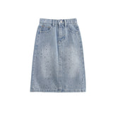 The Rhinestone Embellished Denim Elastic Waist Pencil Skirt from Mabel and Honey is crafted from light blue denim and features a comfortable elastic waistband, front button and zipper closure, belt loops, pockets, subtle distressing with small faded spots throughout the fabric, and stylish rhinestone embellishments. Displayed on a plain white background.